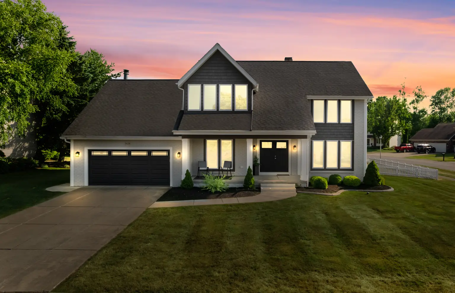 Beautifully maintained modern home exterior with a landscaped front yard, featuring large windows and a welcoming entrance, captured during sunset in North Tonawanda, NY.